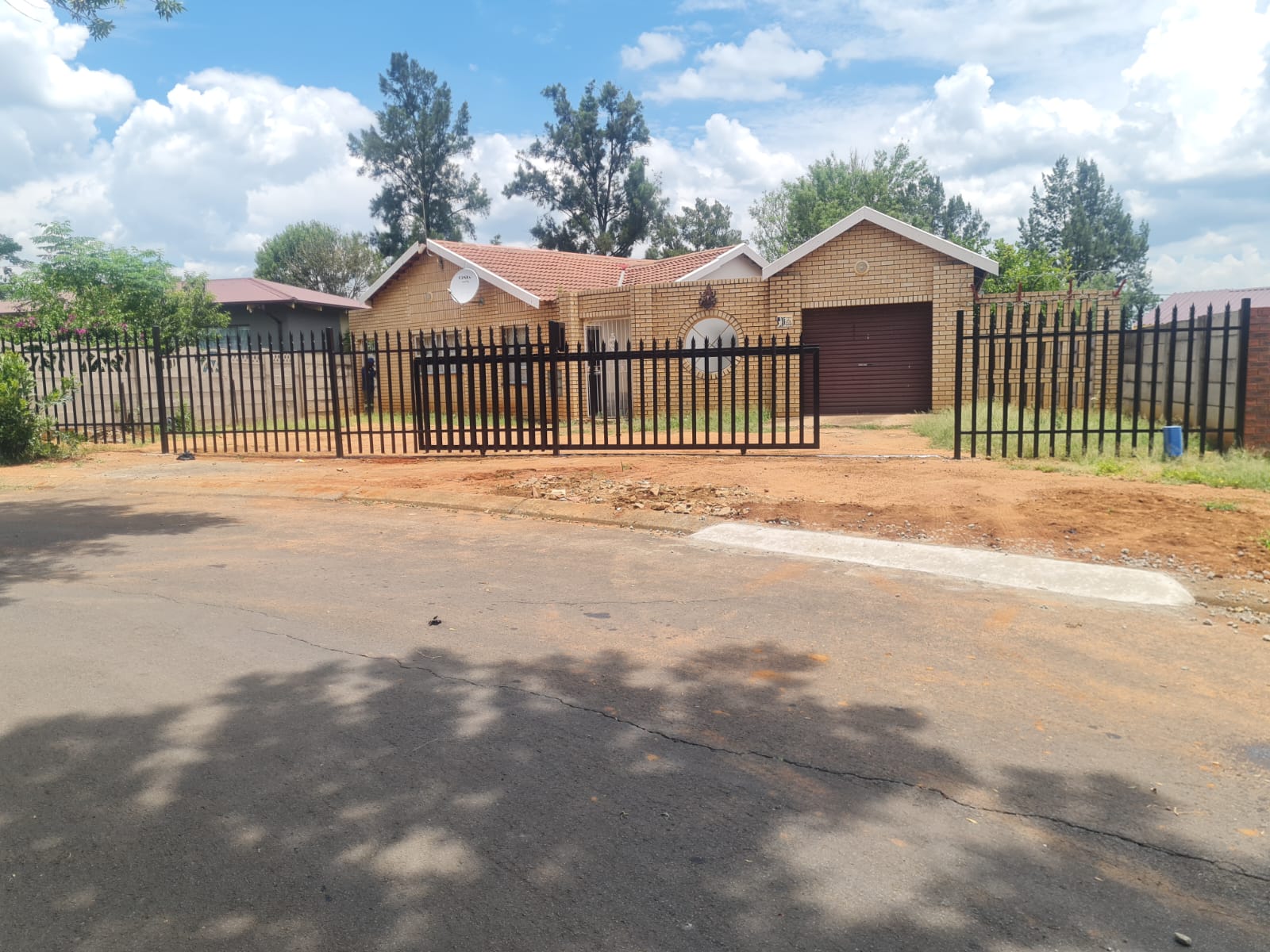 Brick house with red-tiled roof, black metal fence, and driveway